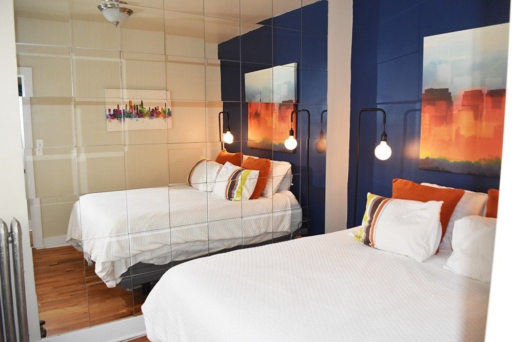 A bedroom with two beds and a large mirror on the wall.