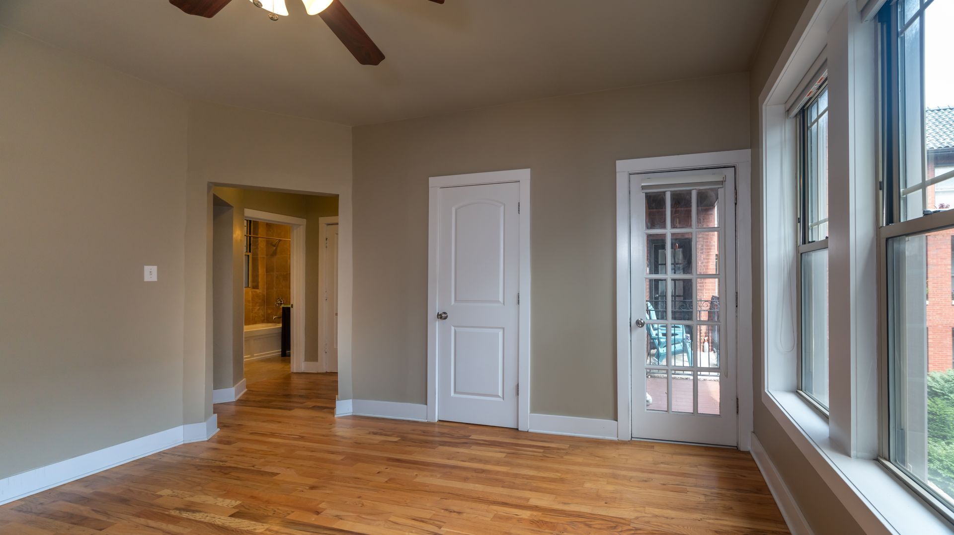 An empty room with hardwood floors and a ceiling fan.