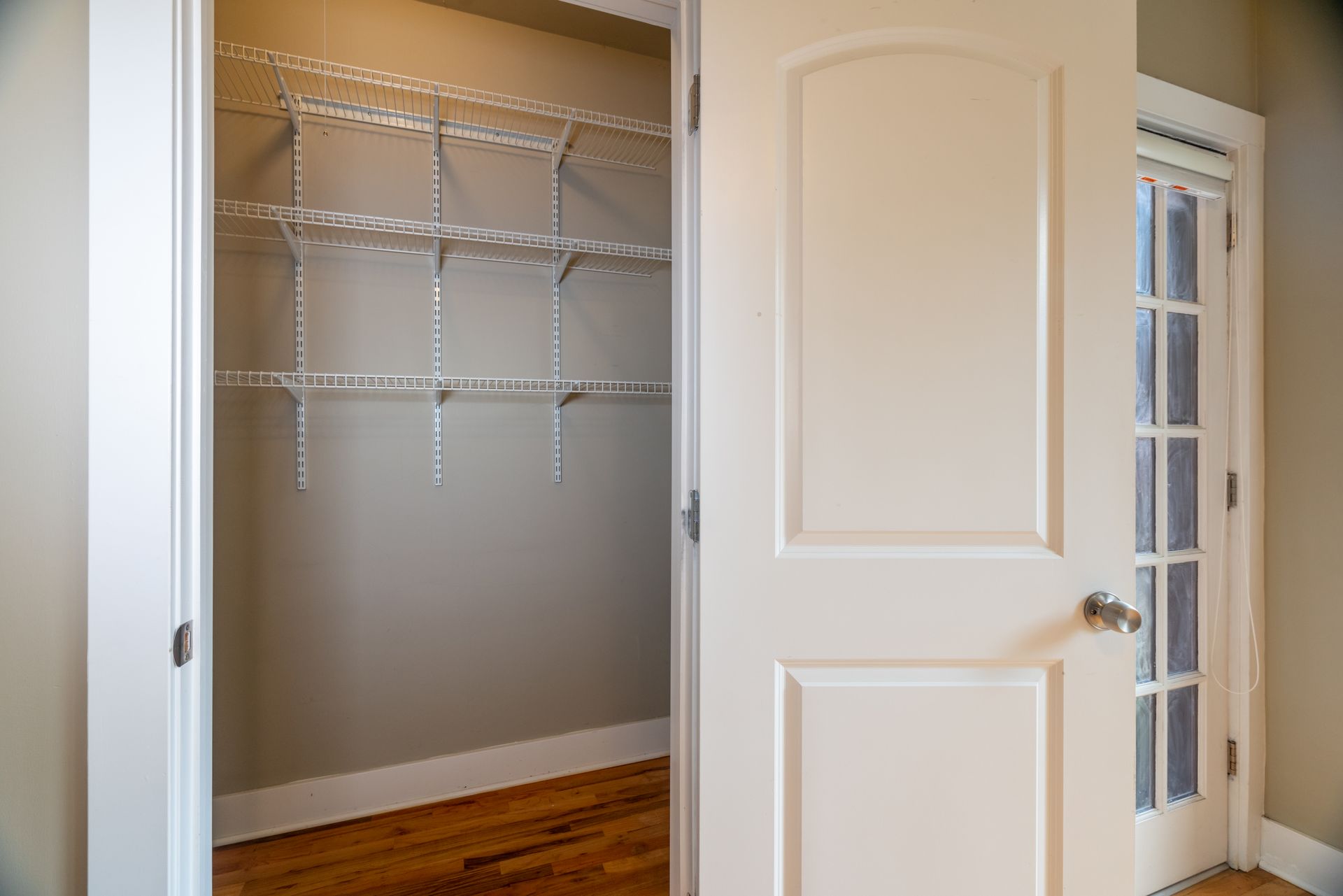 A walk in closet with shelves and a french door.