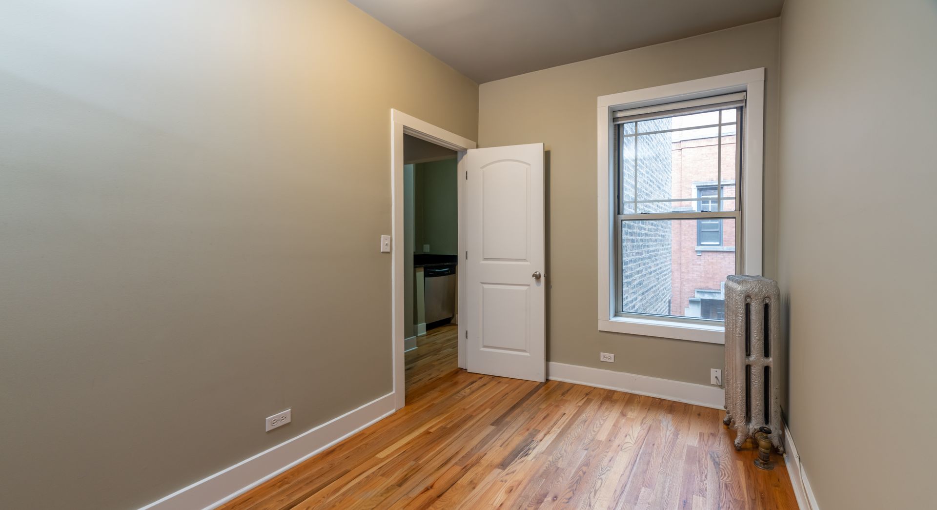 An empty room with hardwood floors and a window.