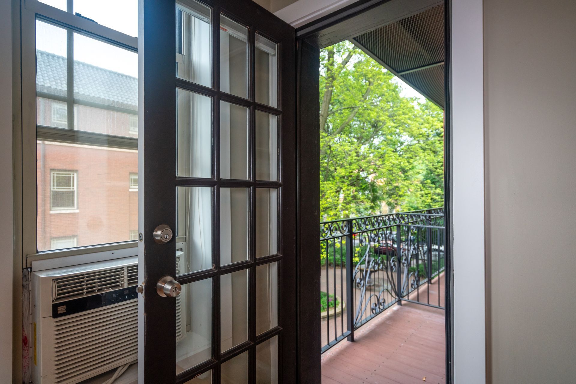The door is open to a balcony with trees in the background.