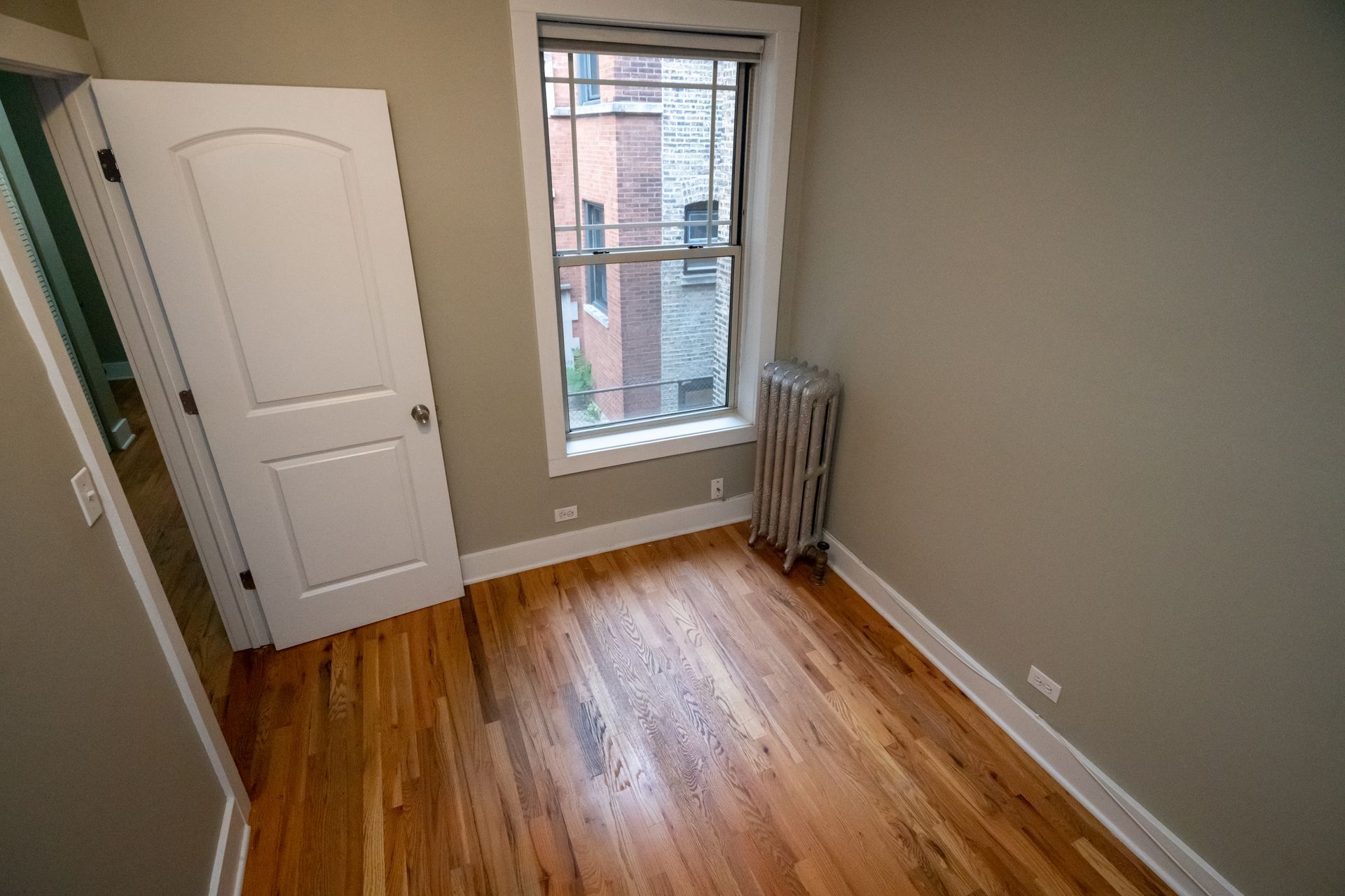 An empty room with hardwood floors and a window.