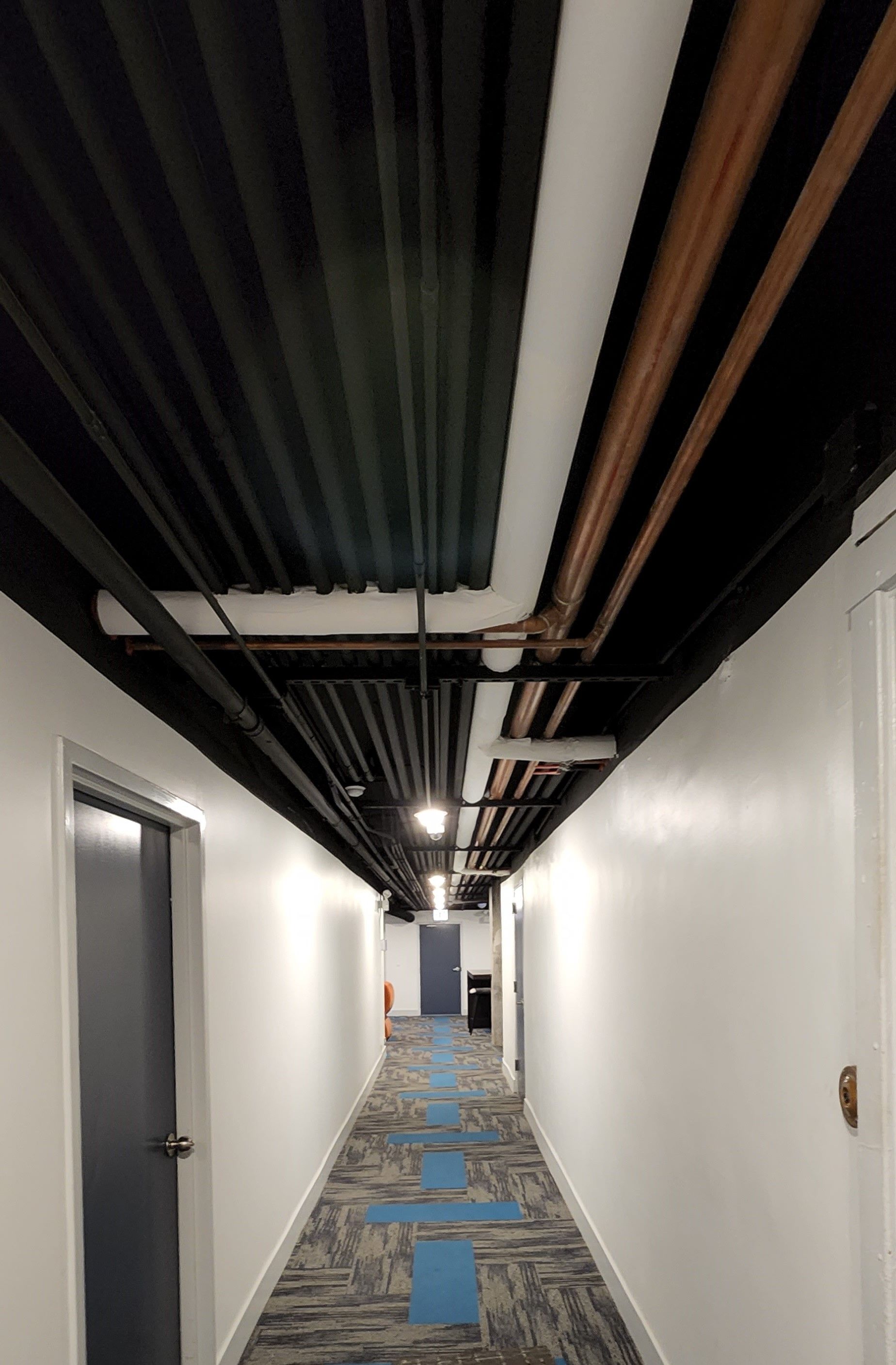 A long hallway with pipes hanging from the ceiling.