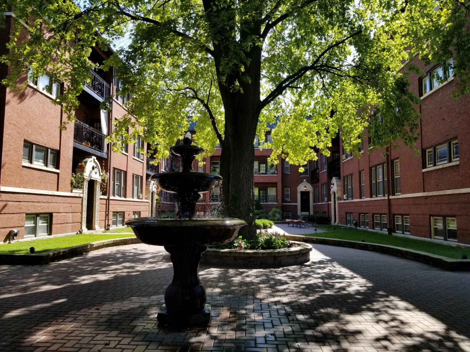 A fountain is in the middle of a courtyard in front of a brick building.