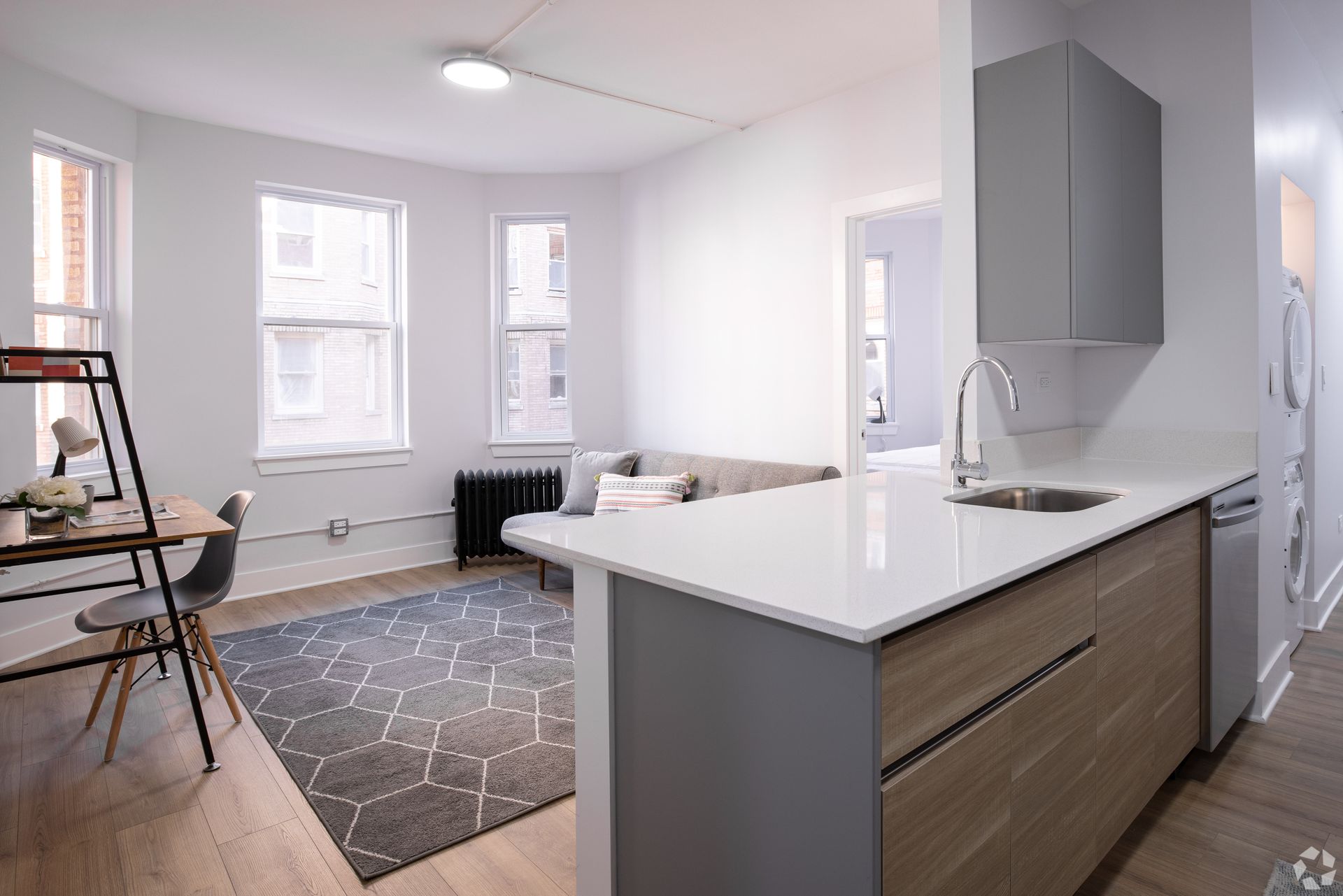 A living room with a couch , table and chairs and a kitchen with a sink.