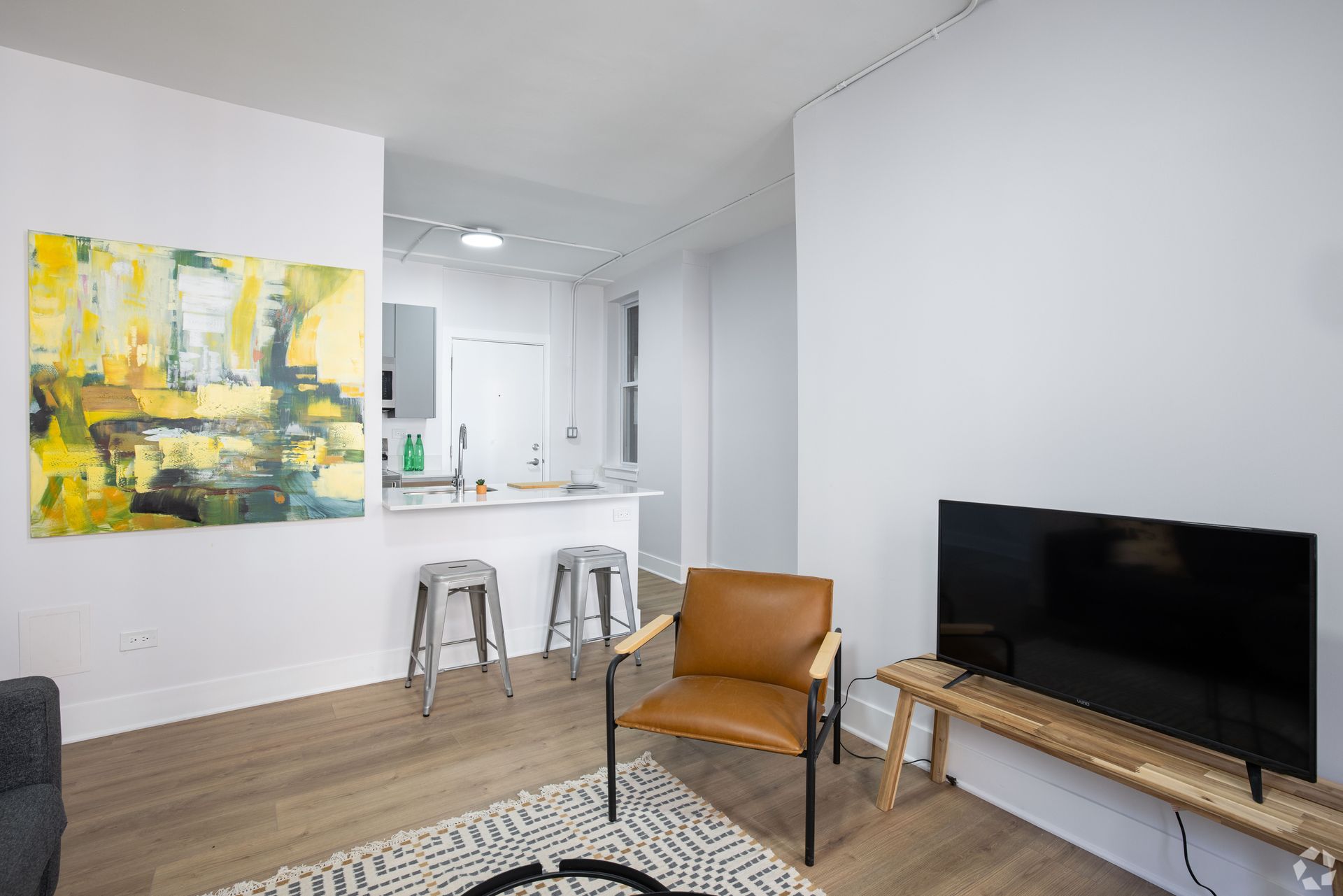 A living room with a chair , television and a painting on the wall.