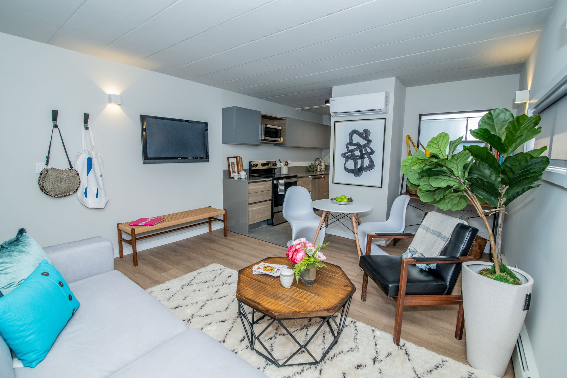 A living room with a couch , chairs , a table and a television.