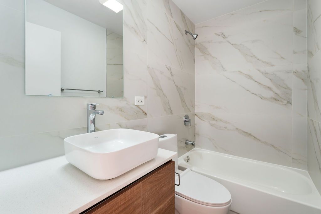 A bathroom with a sink , toilet , tub and mirror.