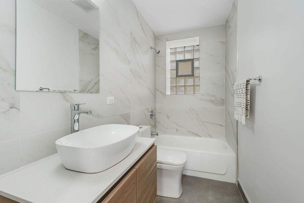 A bathroom with a sink , toilet , tub and mirror.