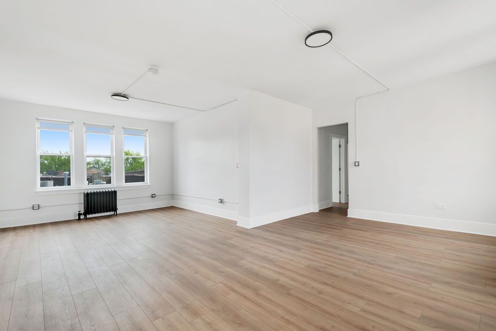 An empty living room with hardwood floors and white walls.
