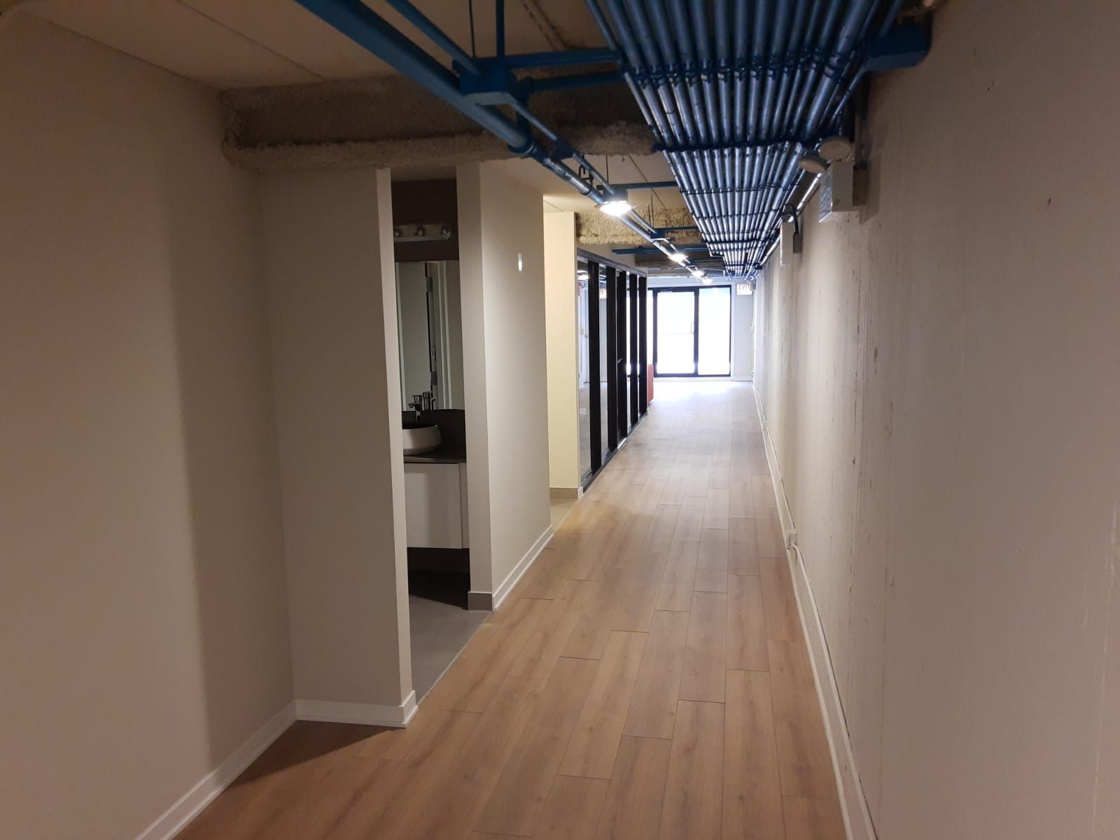 A long hallway with wooden floors and white walls in an office building.
