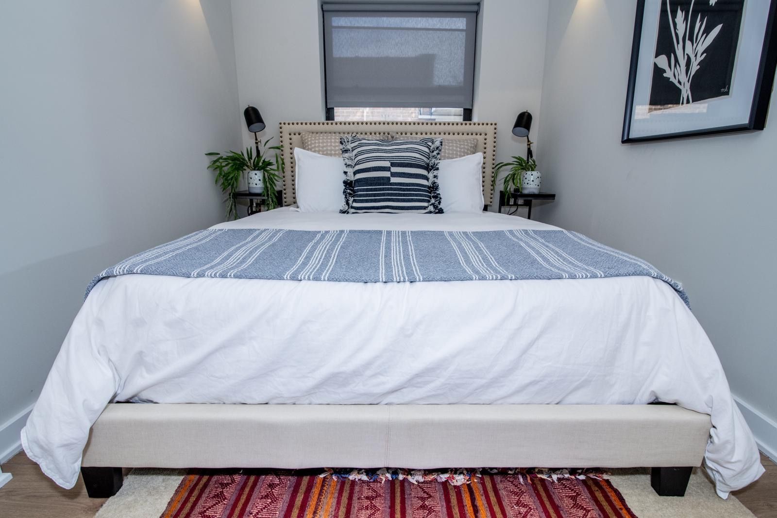 A bedroom with a large bed and a rug on the floor.