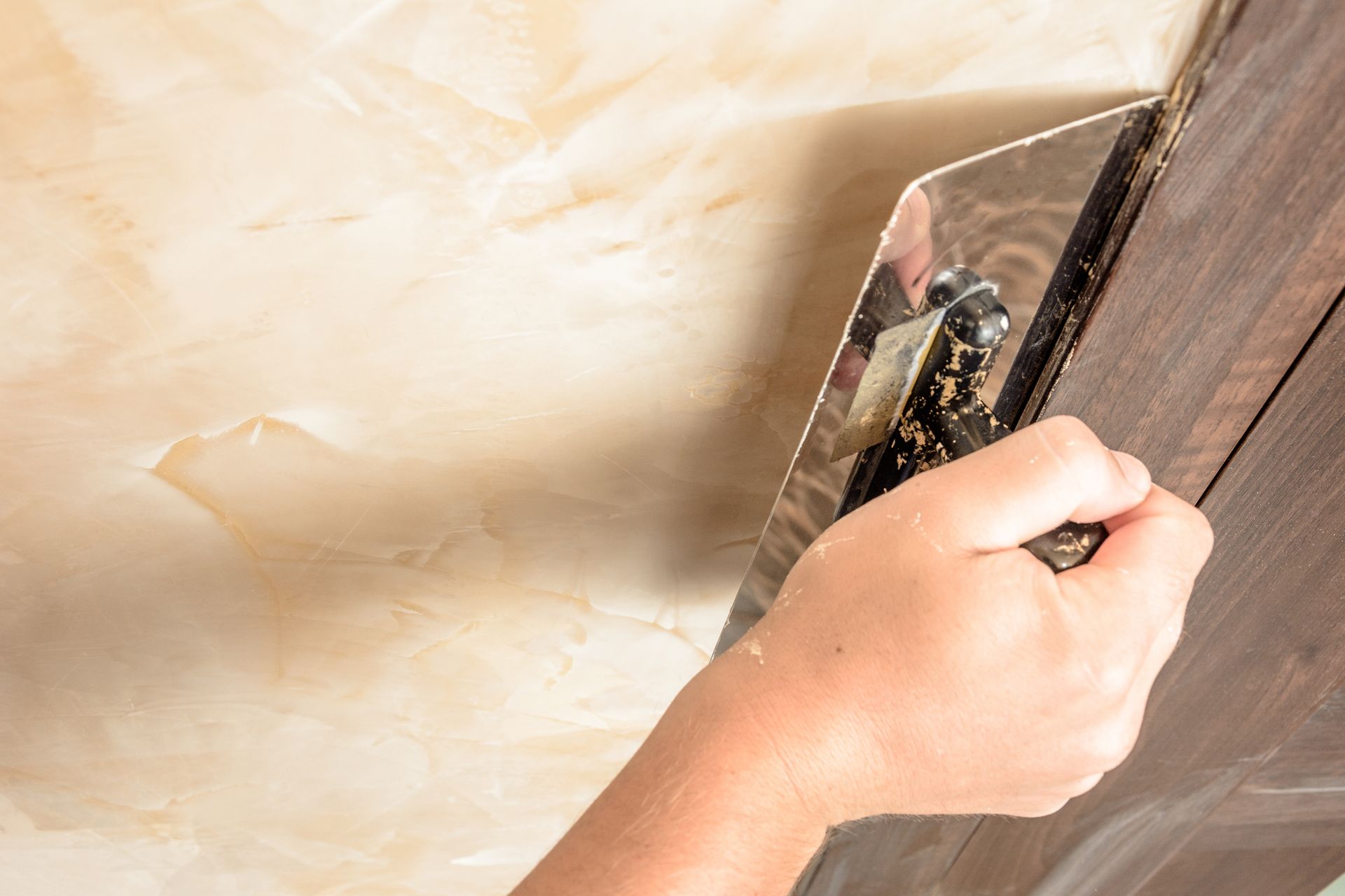 Kitchen with metallic epoxy flooring, dark cabinets, stainless steel appliances, and an island with stools.