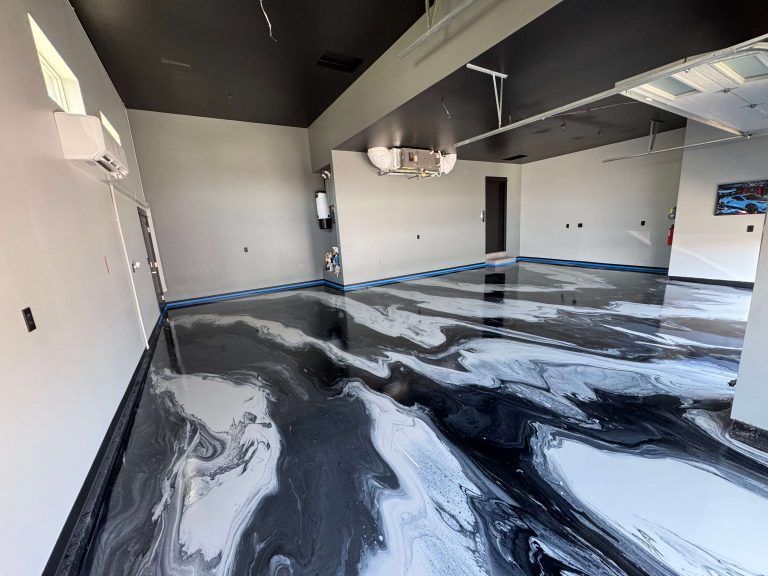 A large, empty room with a glossy, marbled black, white and gray epoxy floor and a black ceiling.