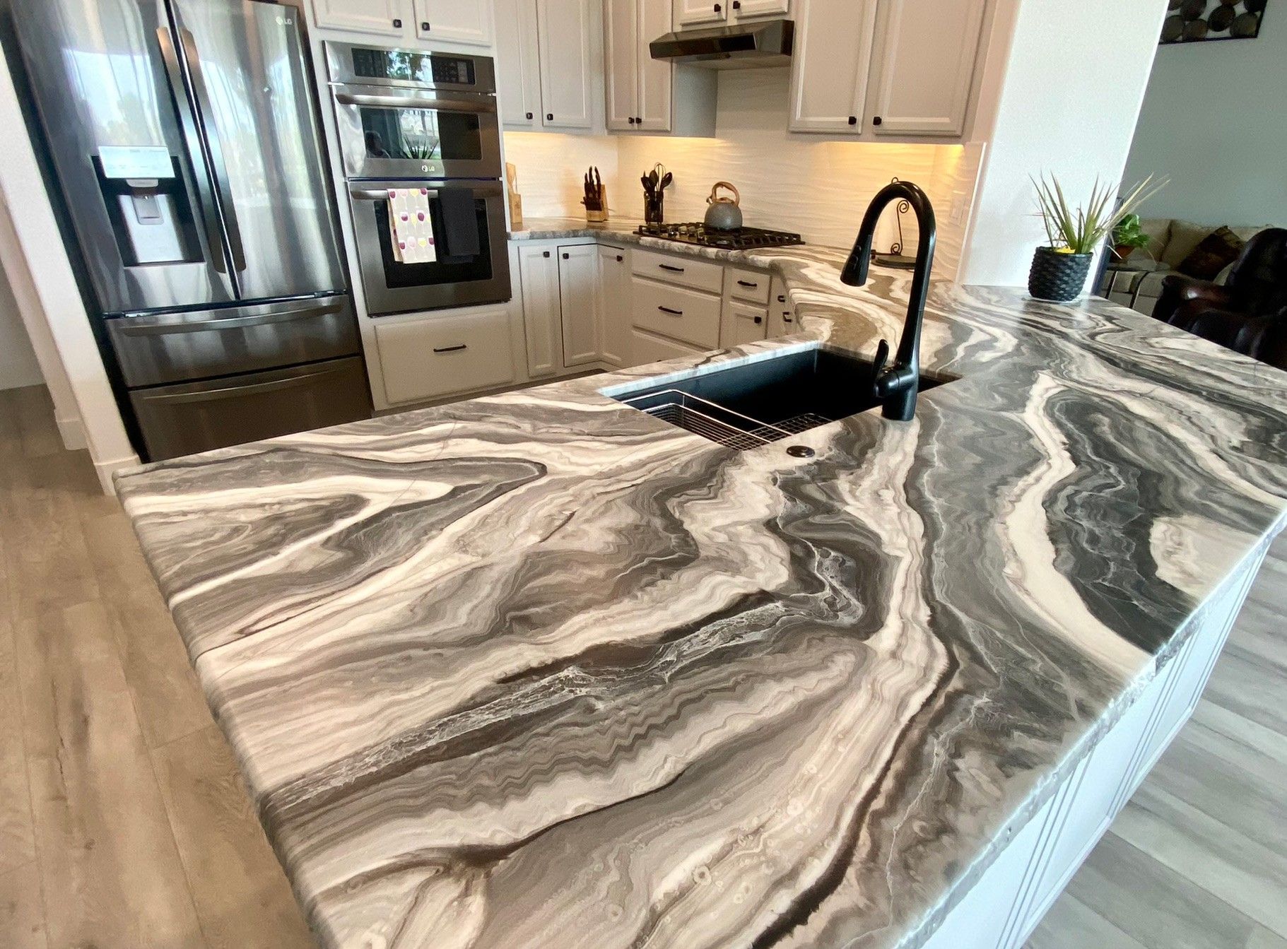 Kitchen with swirling gray and white countertop, black sink and faucet.