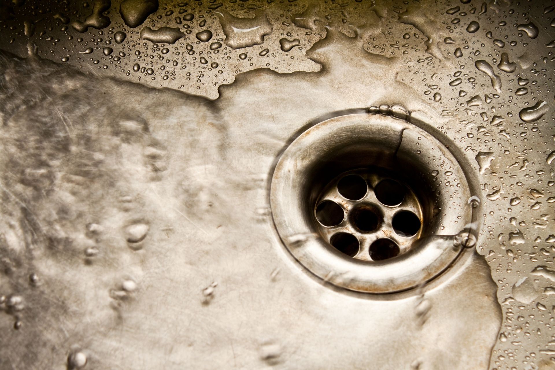 Water flowing into a circular stainless steel sink drain.