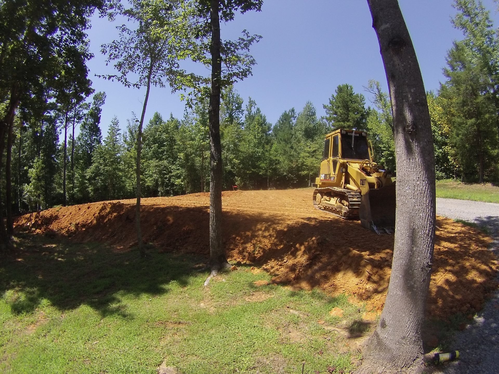 A bulldozer is moving dirt in a field with trees in the background