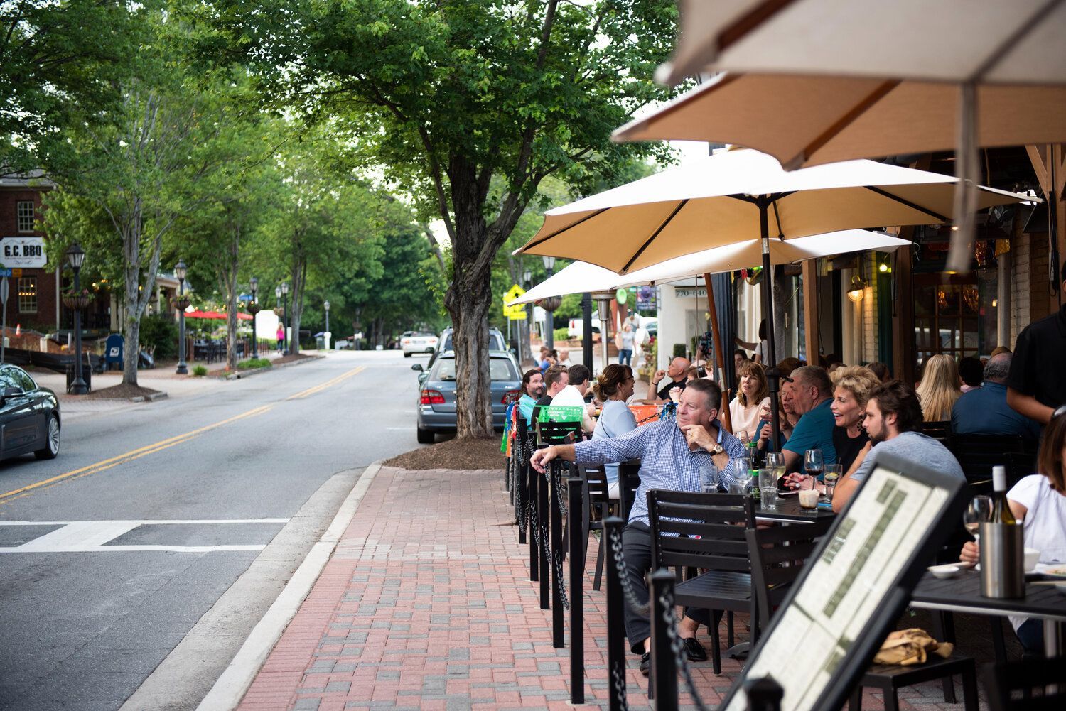 a group of people are sitting outside a restaurant under umbrellas