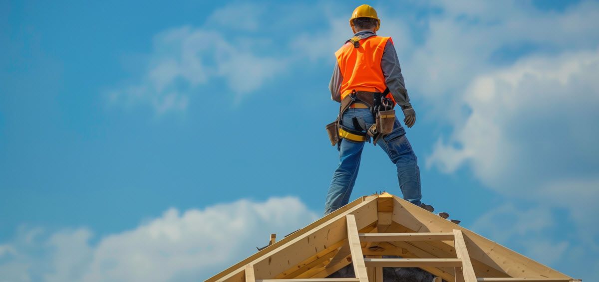 A construction worker is standing on top of a wooden structure.