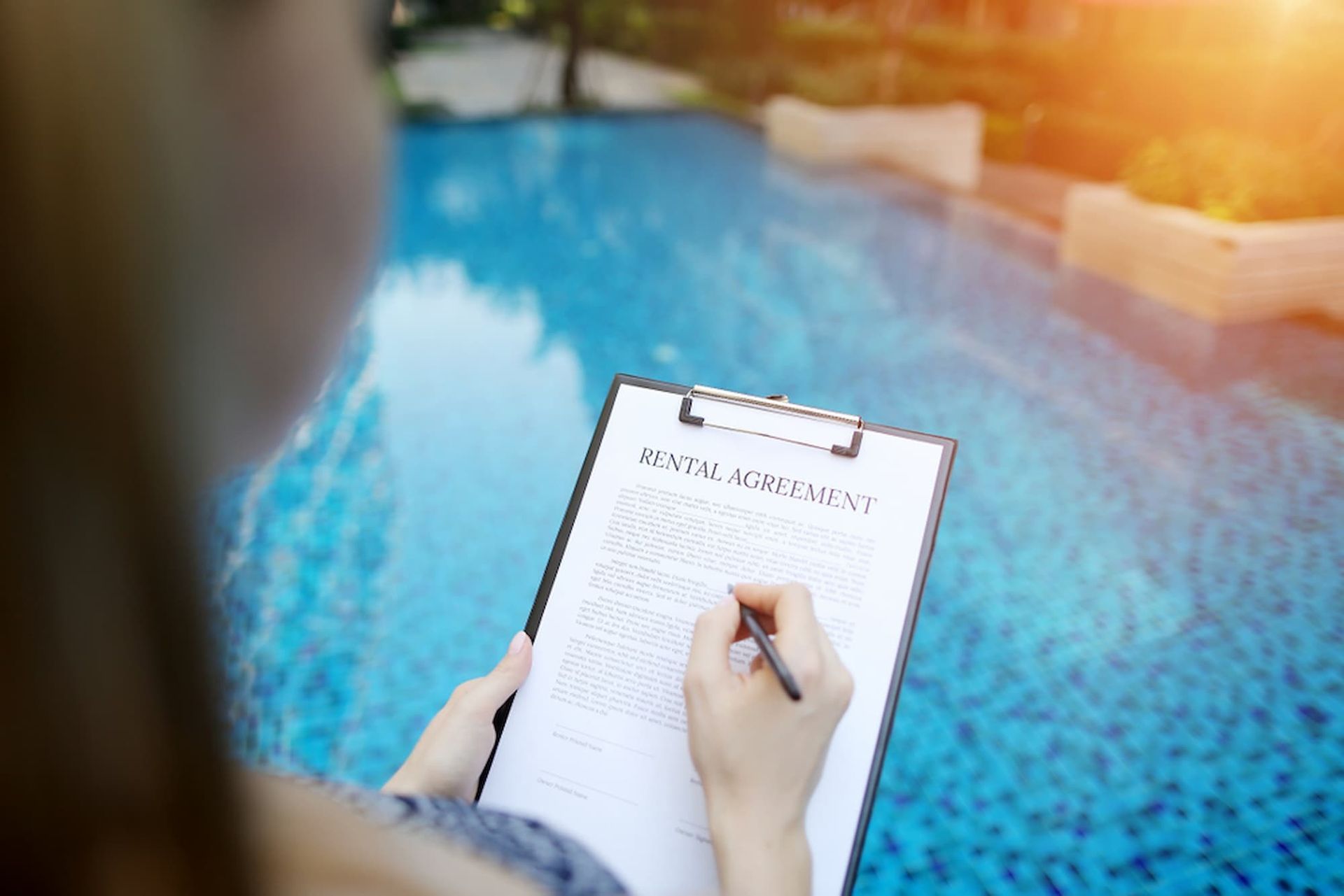 A Woman Is Writing on A Clipboard in Front of A Swimming Pool — Cairns Property Collective in Trinity Park, QLD