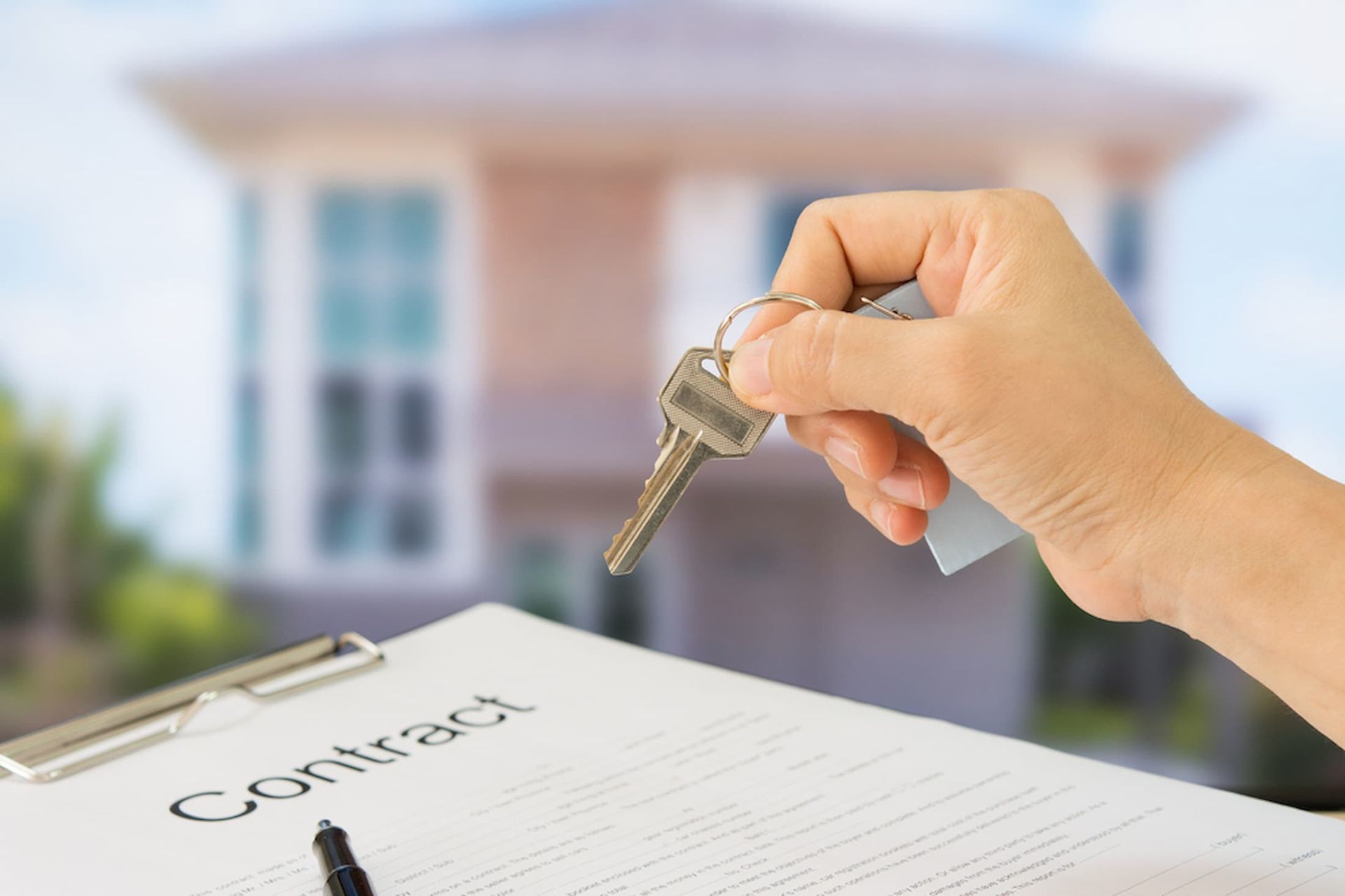 A Person Is Holding a Key Over a Clipboard with A House in The Background — Cairns Property Collective in Trinity Park, QLD