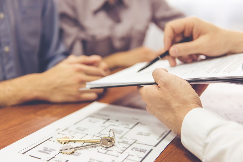 Two People Are Sitting at a Table Looking at a House Plan and Keys — Cairns Property Collective in Redlynch, QLD