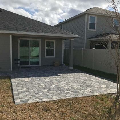 The backyard of a house with a patio and sliding glass doors.