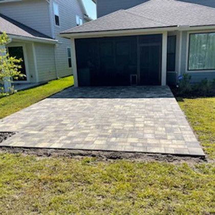 A brick driveway is being built in front of a house.