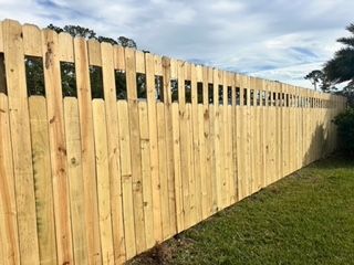 A wooden fence is sitting on top of a lush green field.