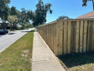 A wooden fence along a sidewalk next to a house.