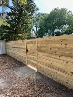 A wooden fence with a gate in the backyard of a house.