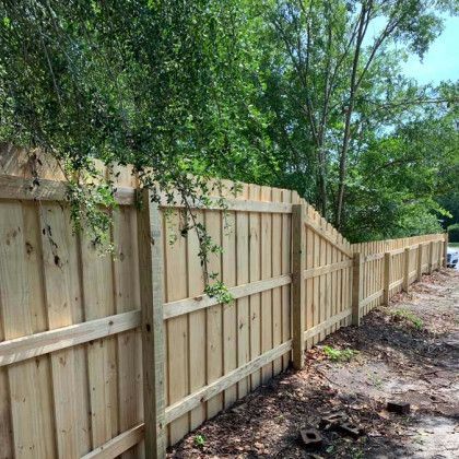 A wooden fence is surrounded by trees on a dirt road.