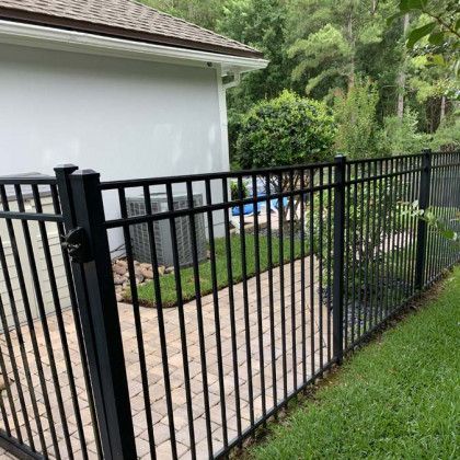 A black aluminum fence surrounds a patio area in front of a house.