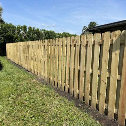 A long wooden fence is sitting in the middle of a lush green field.