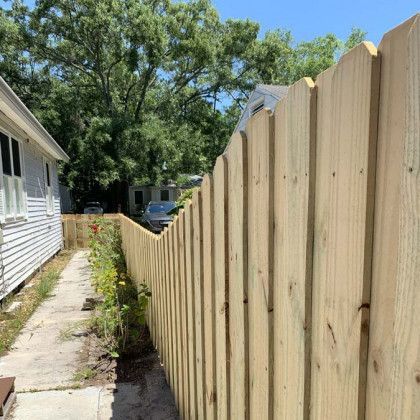 A wooden fence along a sidewalk next to a house.