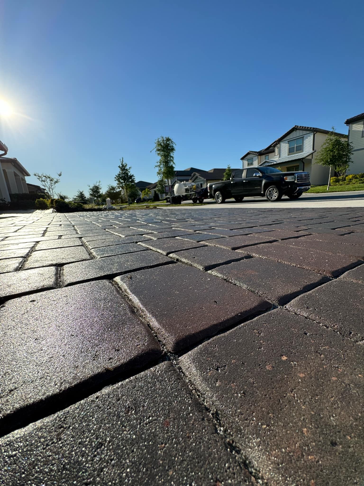 A car is parked on a brick driveway in a residential area.