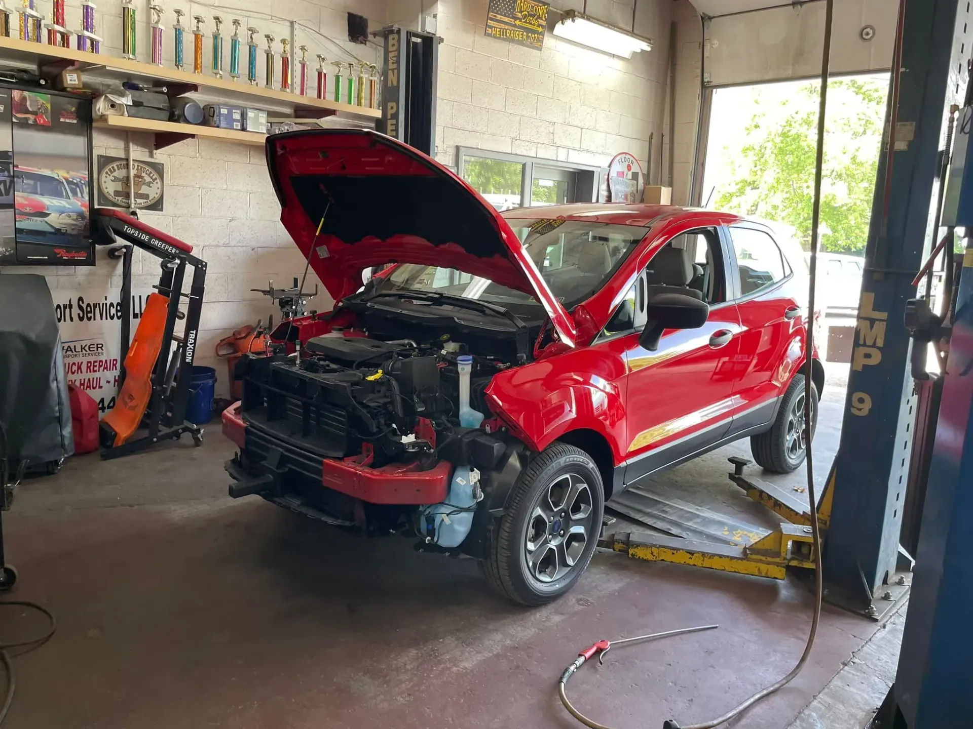 Red Car with Hood Open on a Lift in a Garage | Complete Service Center