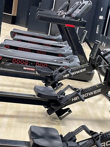 A row of treadmills and rowing machines in a gym.