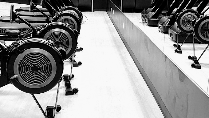 A black and white photo of a row of exercise bikes in a gym.