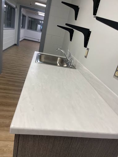 A kitchen with a sink and shelves on the wall.