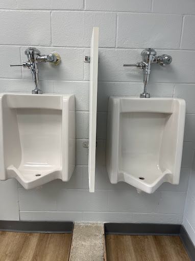 Two urinals are sitting next to each other in a public restroom.