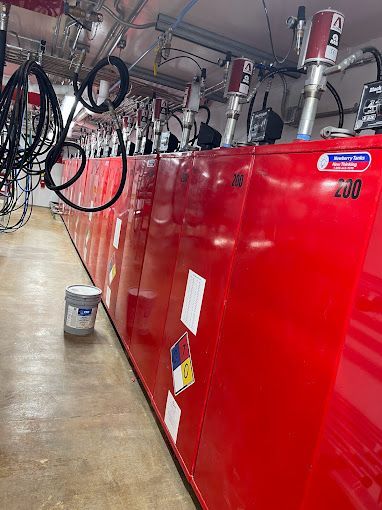 A row of red lockers in a room with a bucket on the floor.