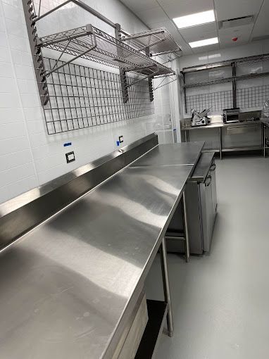A kitchen with stainless steel counter tops and shelves.