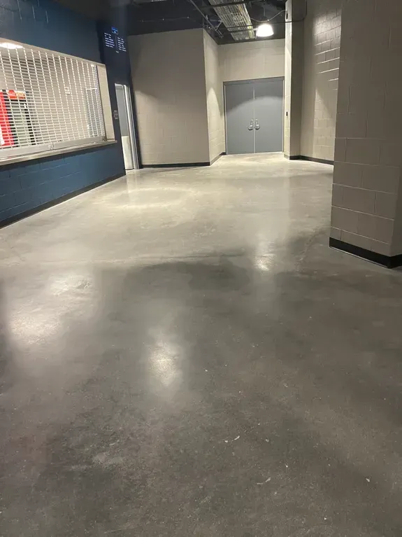 A large empty room with a concrete floor and columns.