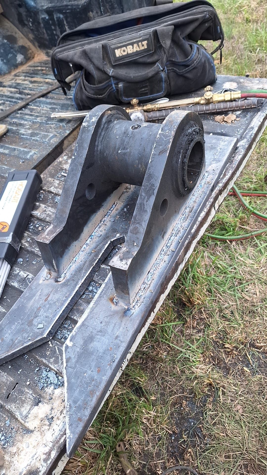 A piece of metal is sitting on top of a table next to a tool bag.