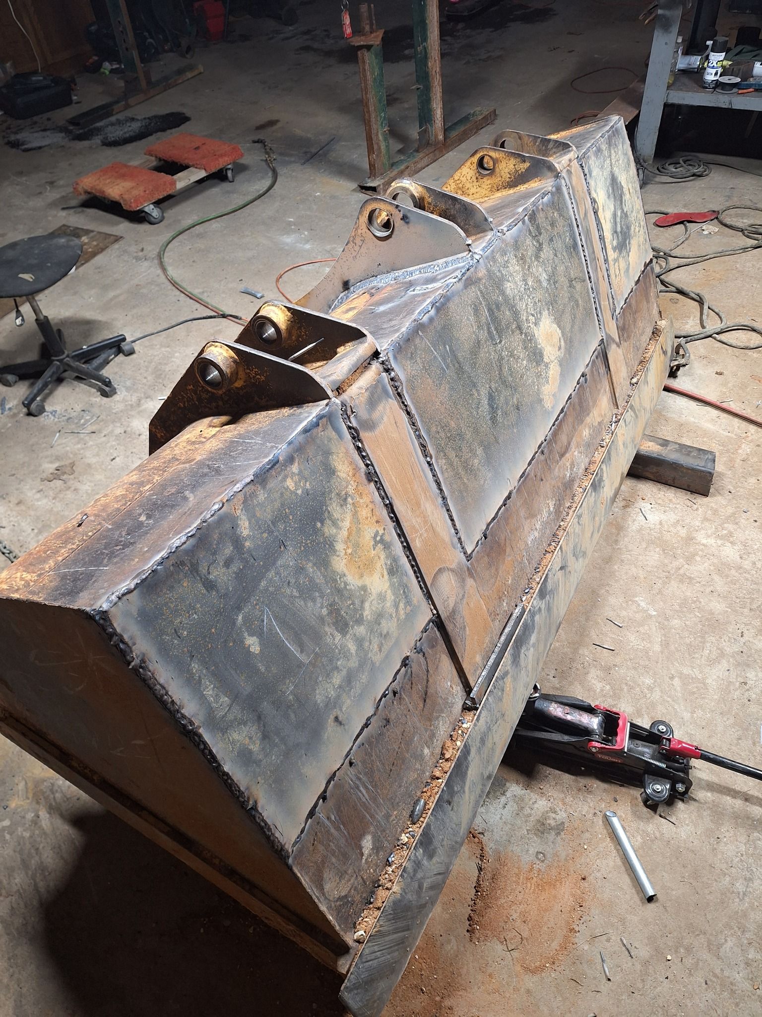 A large metal bucket is being repaired in a garage.