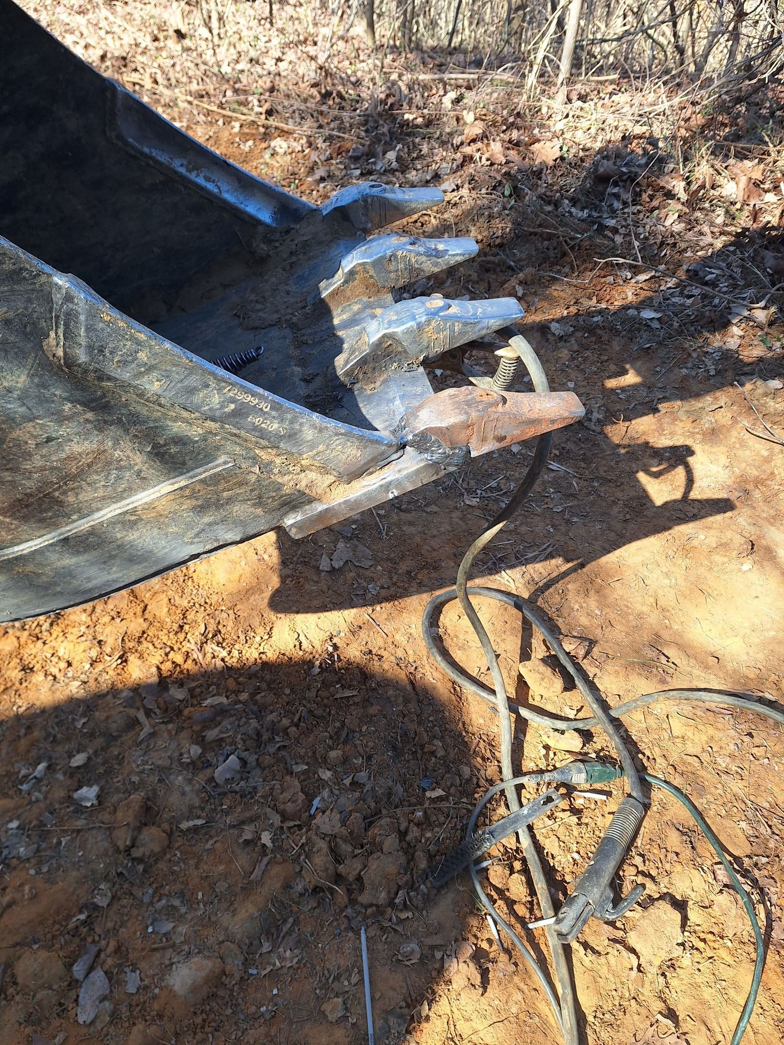 A close up of a bulldozer bucket with a hose attached to it.