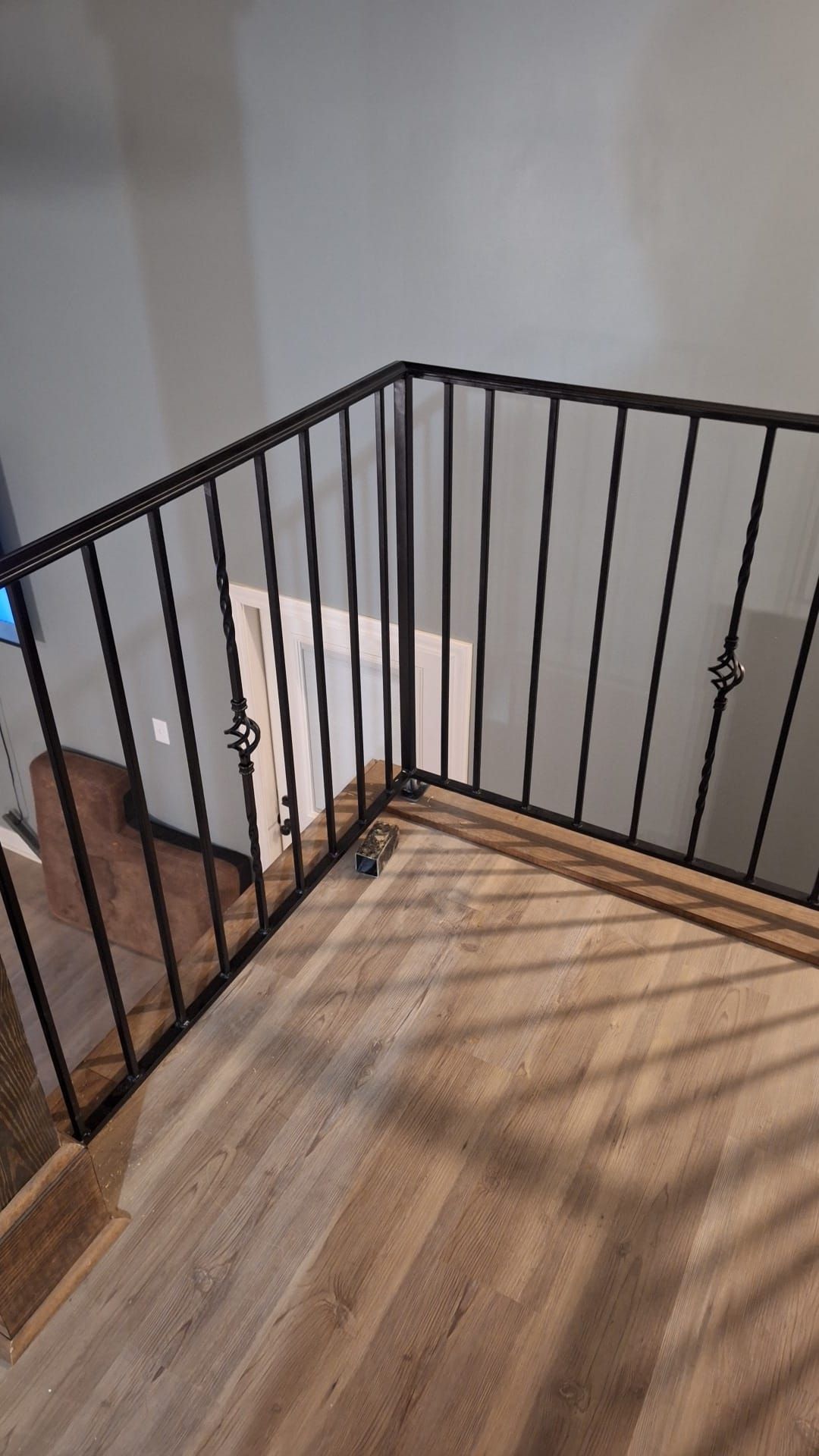 A staircase with a wrought iron railing and a wooden floor.