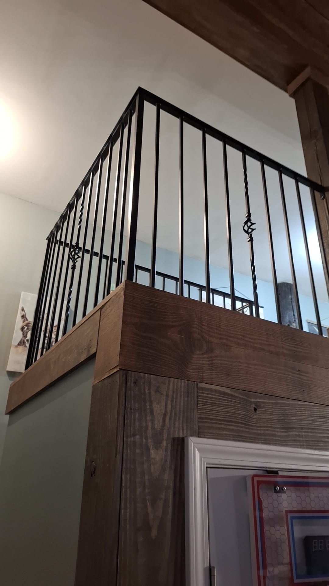 A balcony with a wrought iron railing and a wooden beam.