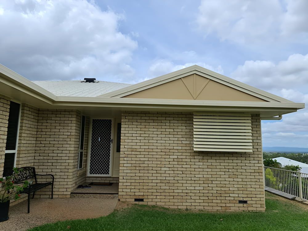 A White Brick House With a White Roof and a Bench in Front of It — BK Painting & Property Maintenance in Gracemere, QLD